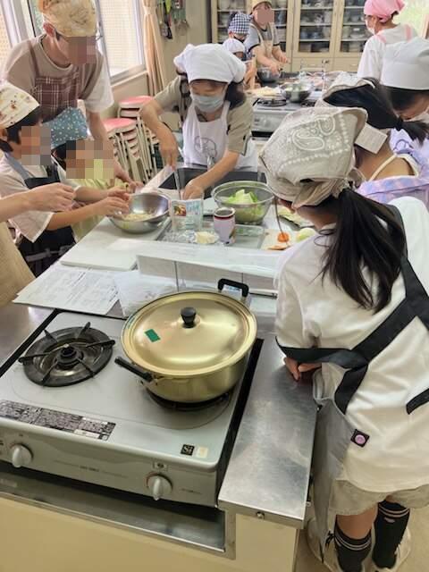 調理台でお父さんと子ども、講師とお友達同士で参加した女の子が調理をしている様子