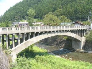 綺麗な小川に大きな橋がかかっている緑豊かな名栗地区のイメージ写真