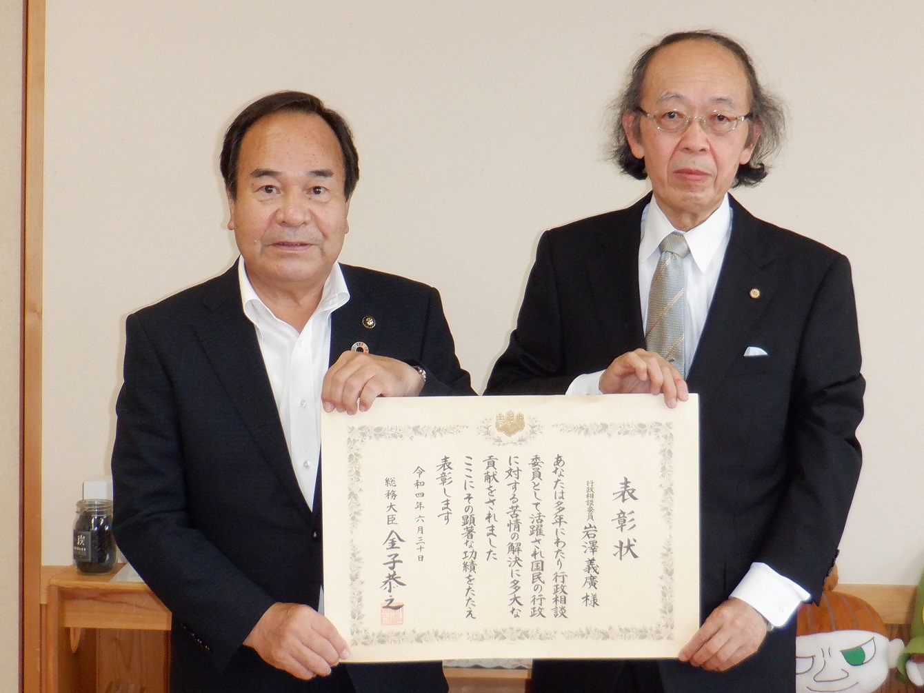 総務大臣表彰を受賞された岩澤義廣様と市長が表彰状に手を添えた写真