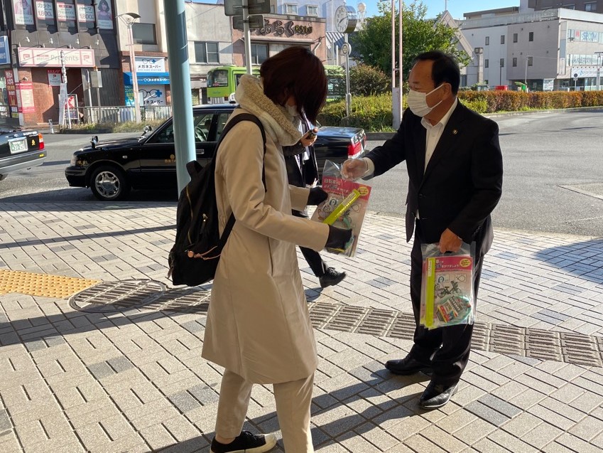 道行く市民にキャンペーンの冊子等が入った袋を手渡す市長の写真