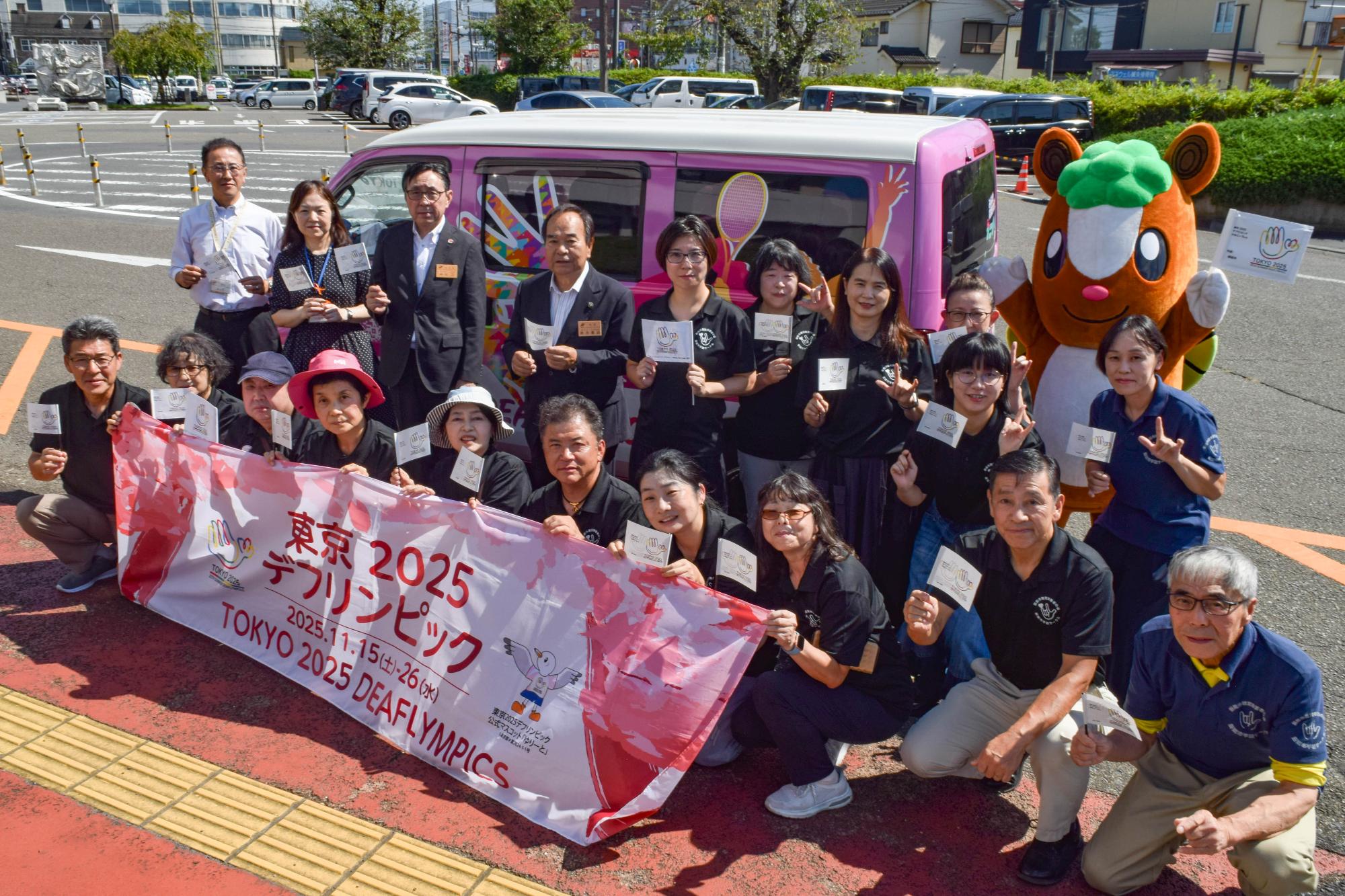 PRカーの前で横断幕を広げ集合写真