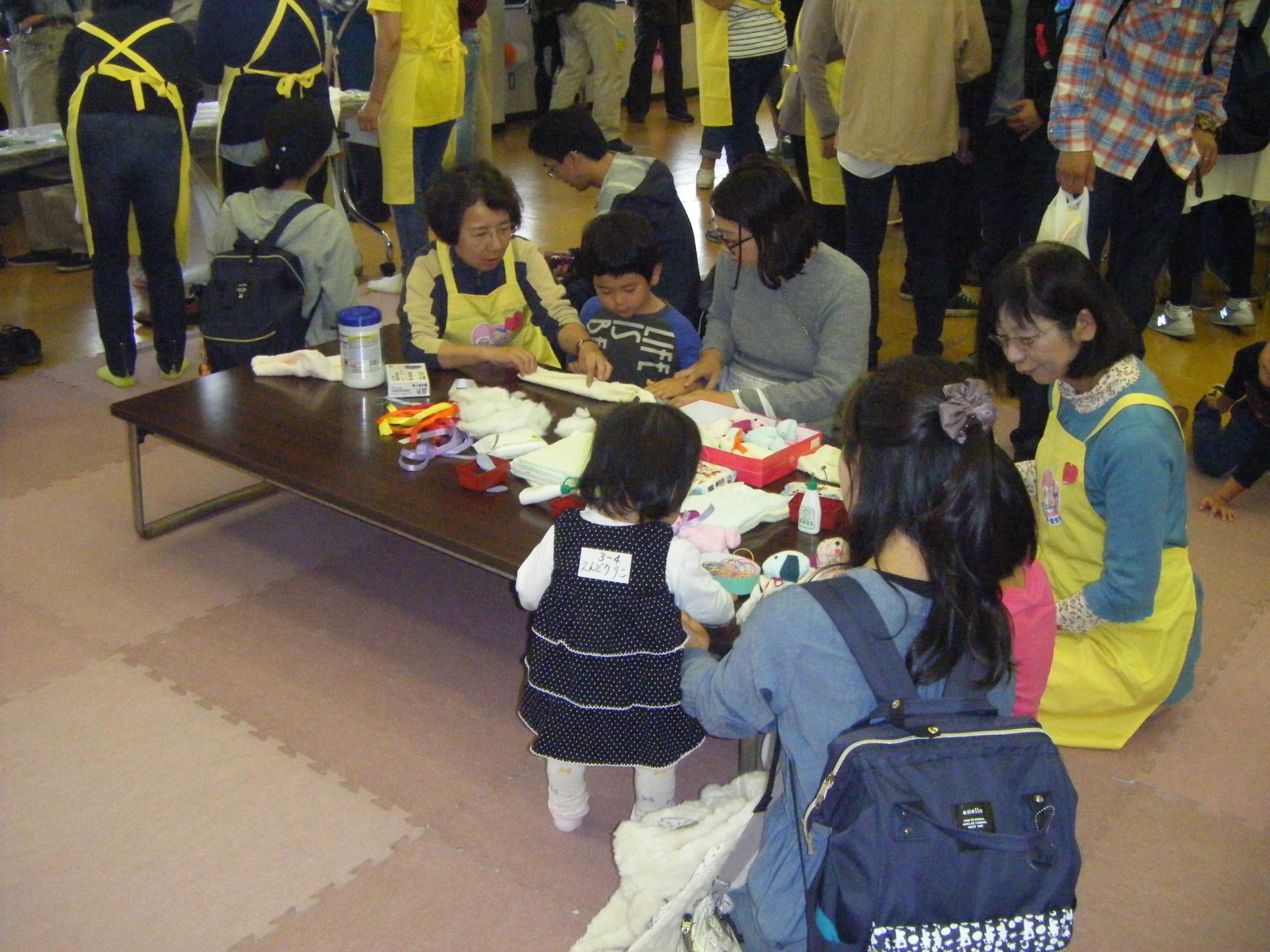 愛育会の皆さんが子どもたちに縫い物を教えている様子の写真