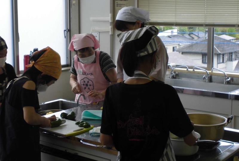 親子クッキング教室にて、食生活改善推進員が小学生に調理指導する様子。