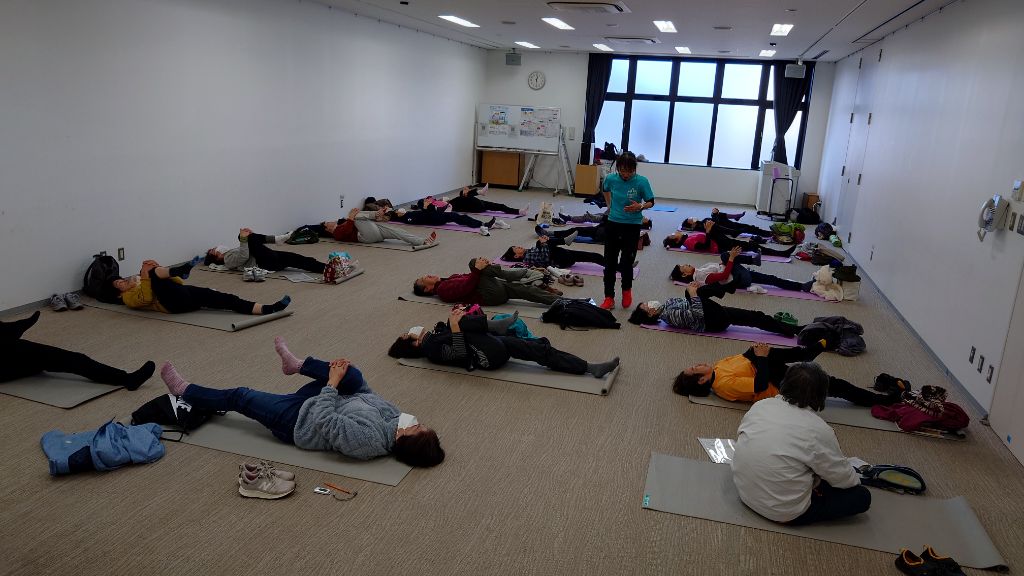 令和5年度に開催された講座の様子。室内で参加者がヨガマットに仰向けになりクールダウンを行っています。