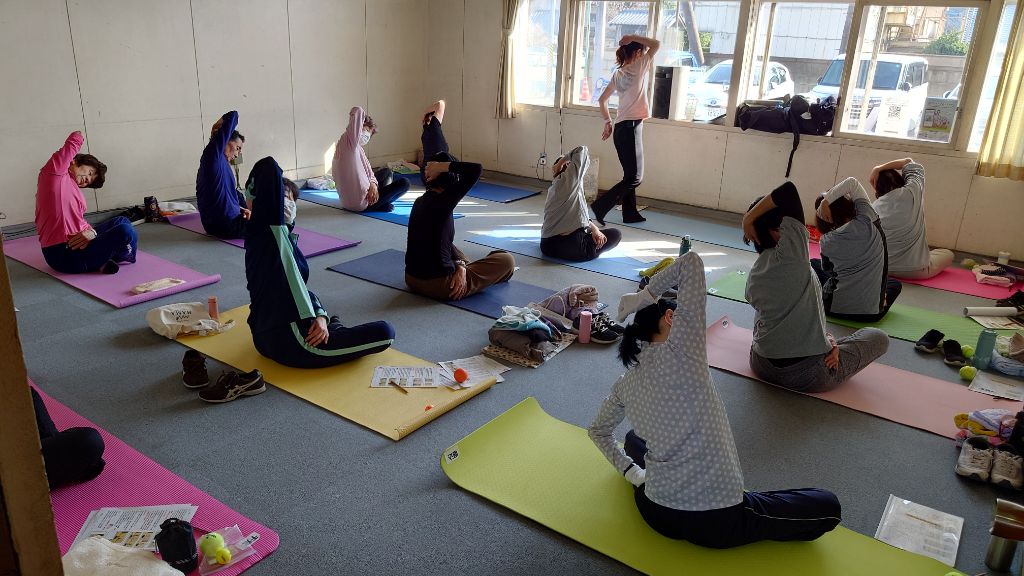 令和6年度に開催された講座の様子です。胡坐をかいて座り体を横に曲げて、脇を伸ばすストレッチを行っています。