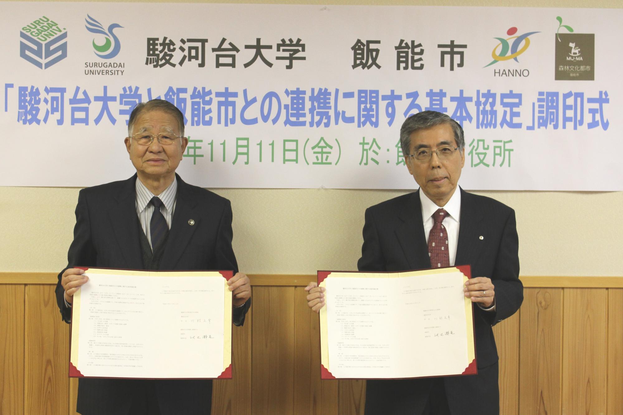 飯能市長と駿河台大学学長が協定書を手に持ち並んで撮影している写真