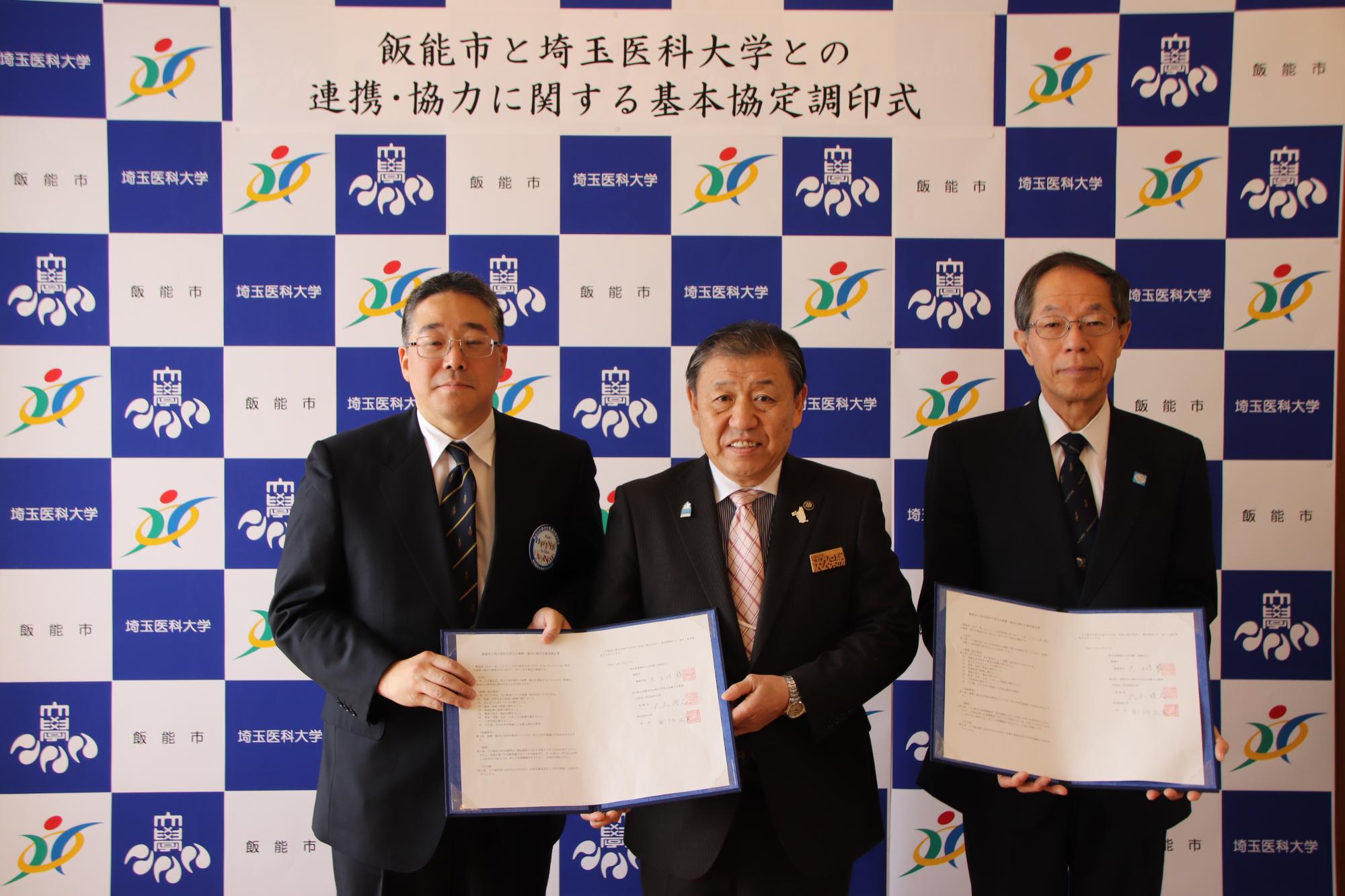 市長と埼玉医科大学理事長、埼玉医科大学学長が協定書を手に持ち並んで撮影している写真