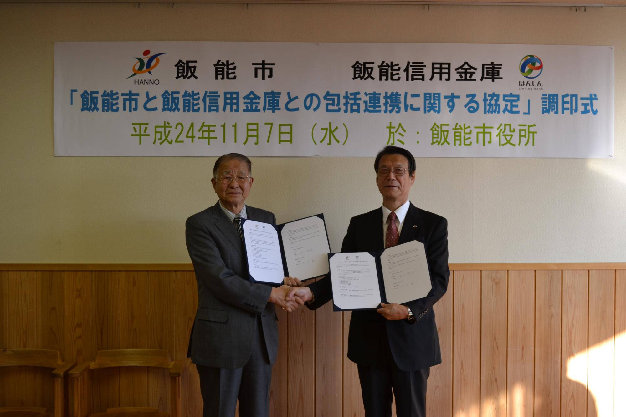市長と飯能信用金庫理事長が協定書を手に持ち並んで撮影している写真