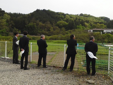 5人の議員がフェンスの前に並び、緑の山々を見ている様子の議員の写真