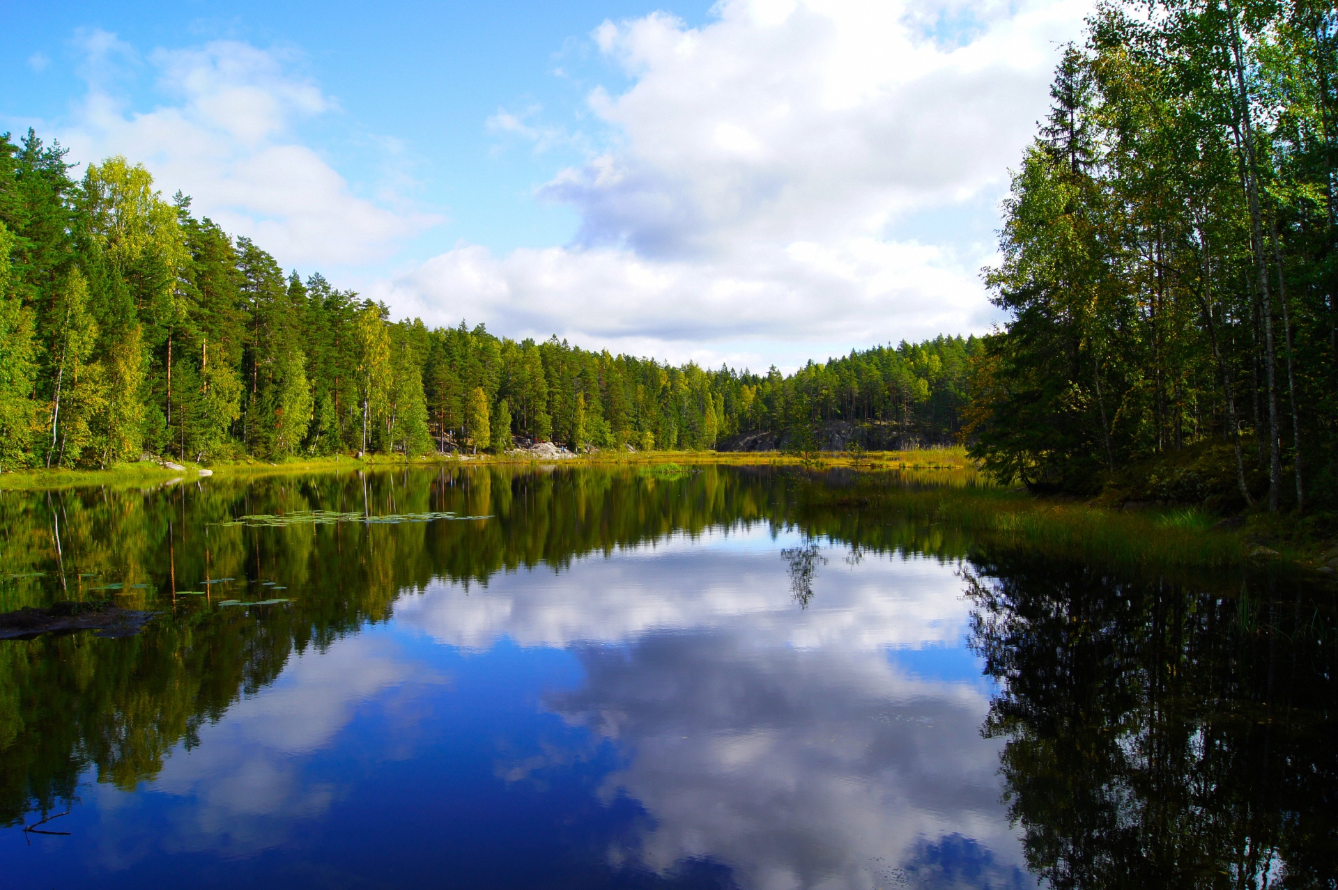 緑に囲まれた大きな湖面に青空に白い雲が映し出されているフィンランドの風景写真