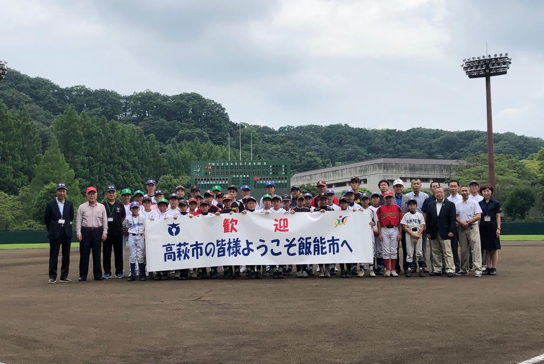 野球場にて撮影された茨城県高萩市との友好都市交流会の集合写真