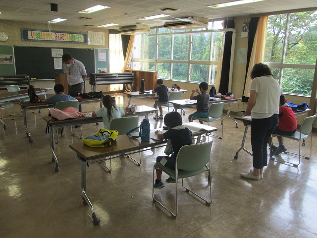 公民館で小学生たちが、先生方に教わりながら宿題に取り組んでいる様子の写真