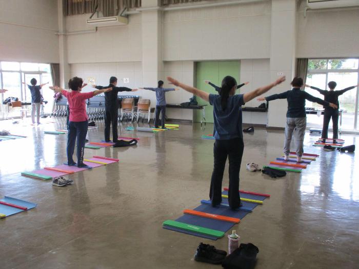 講師の指導の下、バランススティックを使った体操をする参加者の写真
