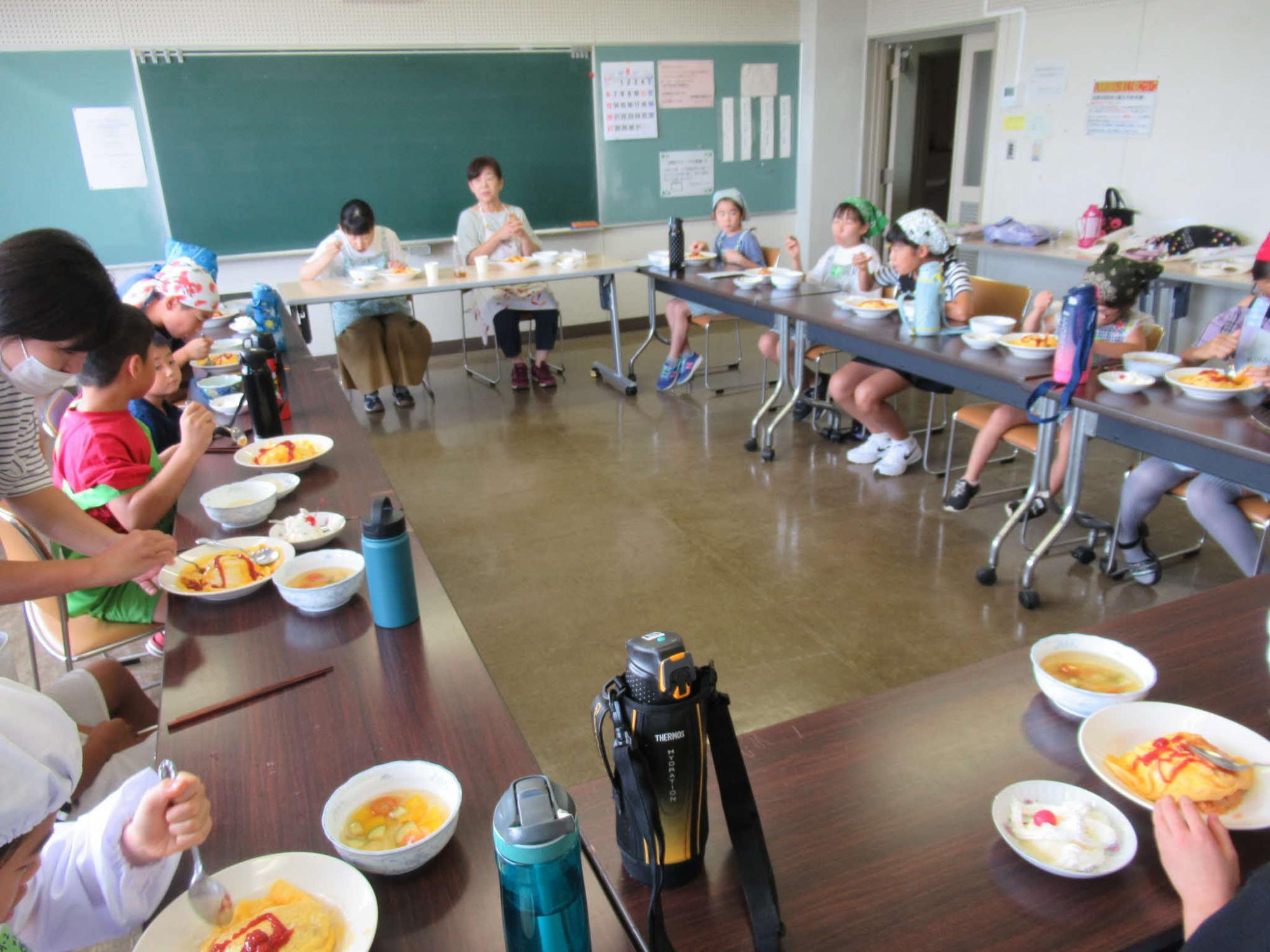 みんなで調理した料理を講師と共に会食する参加者の写真