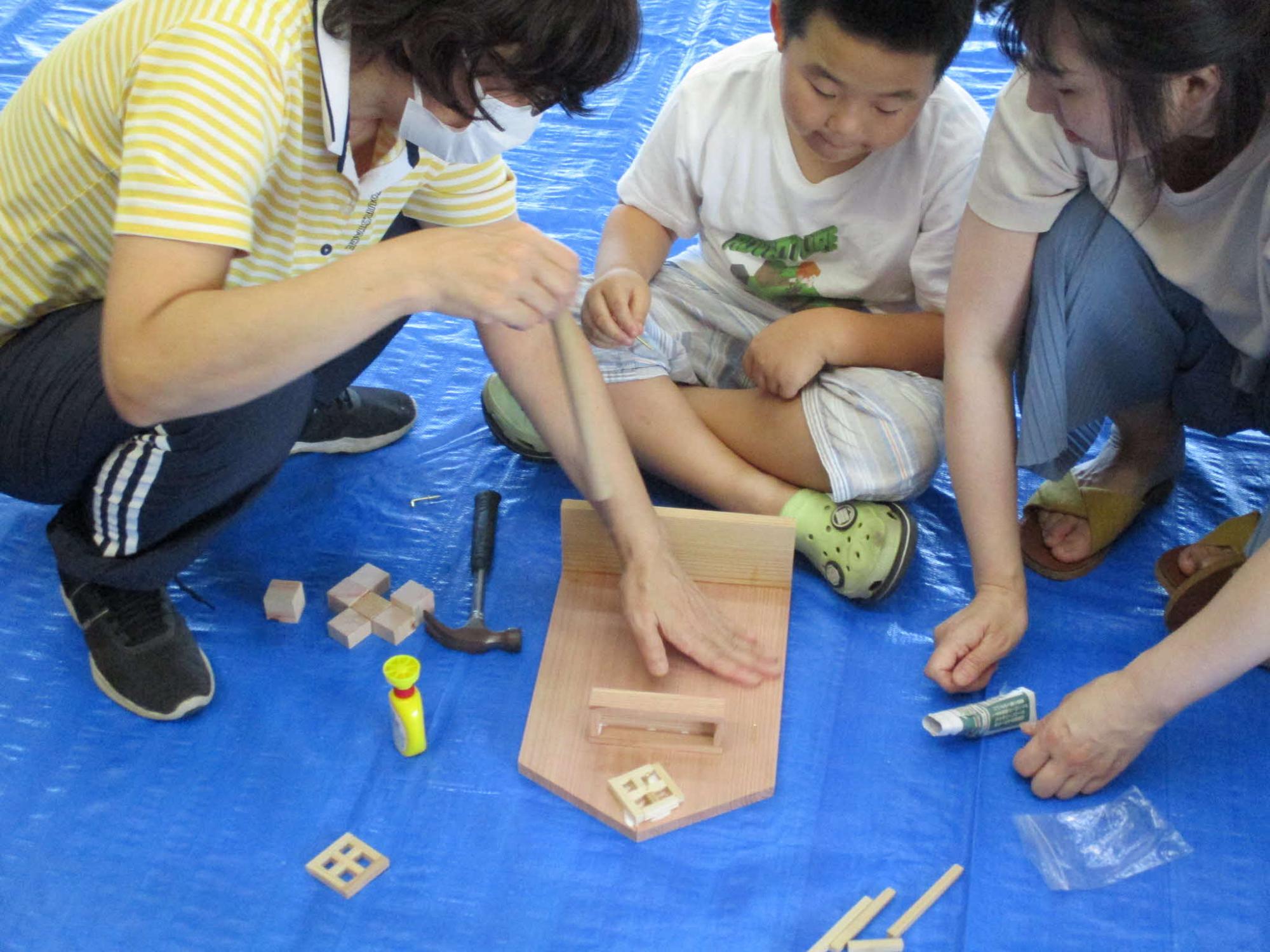 西川材製キーラックを講師の指導の下に作成する参加者親子の写真