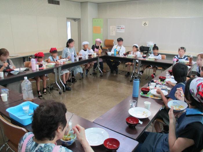 調理した料理を行使などを交えて参加者全員で会食している写真
