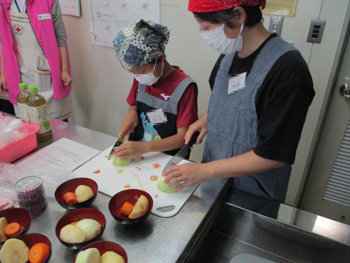一人分ずつお椀に分けられた野菜を切る参加者の写真