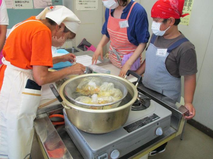 沸騰した鍋でご飯を炊いた後、ビニル袋に入れたカレーを煮込んでいる写真