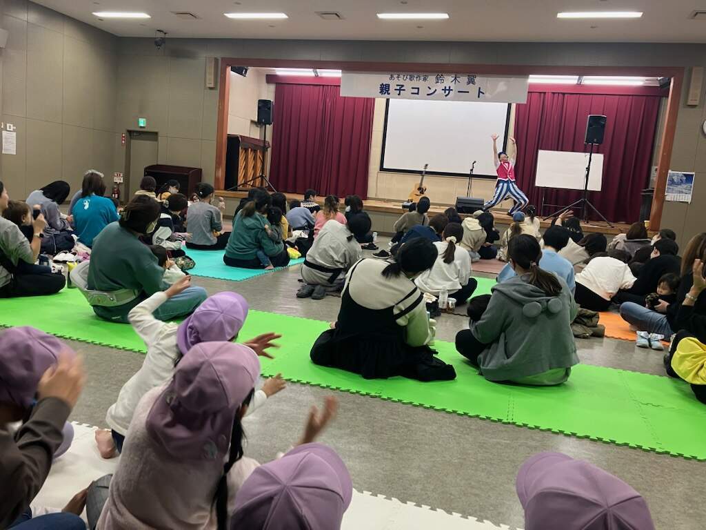 集会室に観覧者119名が座り出演者の鈴木翼さんの歌に合わせ身体を動かしにぎやかな様子