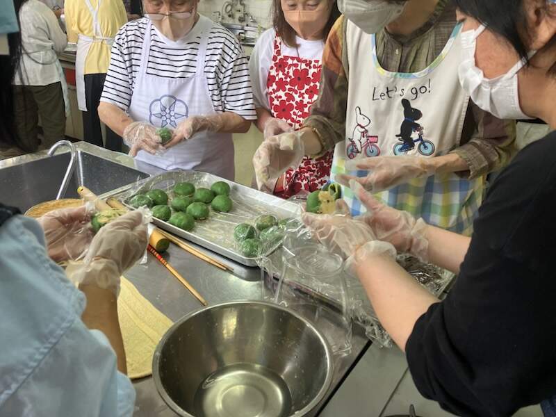 参加者の皆さんが草もちにあんこを包み形を整えている様子