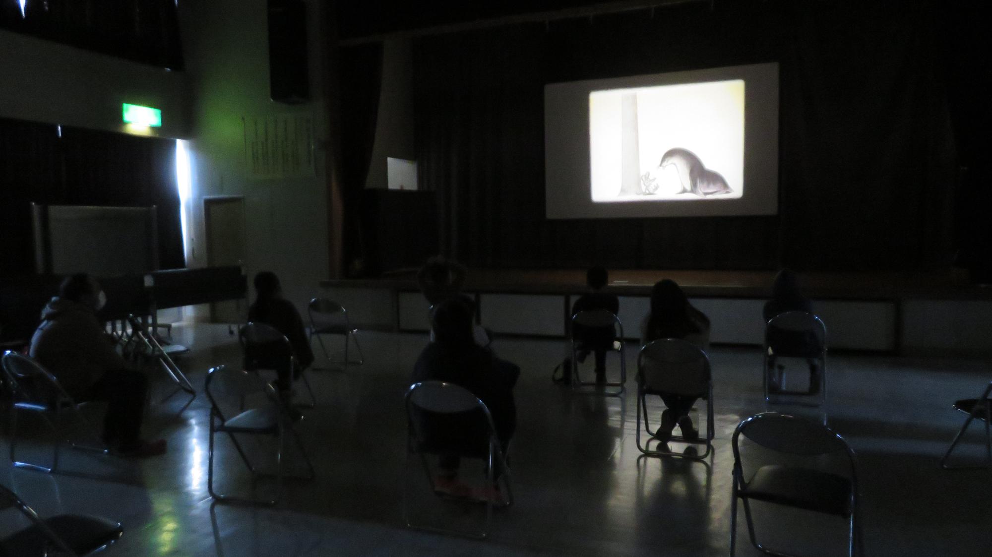 冬休み映画会に参加した児童たちが、暗い室内で映画を観ている様子の写真