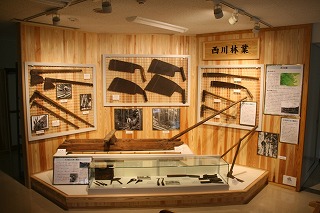 ノコギリやソリなどの「西川林業」の道具が展示されている展示コーナーの写真