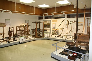 鉄鍋やカゴなど様々な道具が展示されている「くらしの展示室」の写真