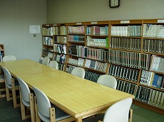 本棚、長机、椅子のある図書室内の写真