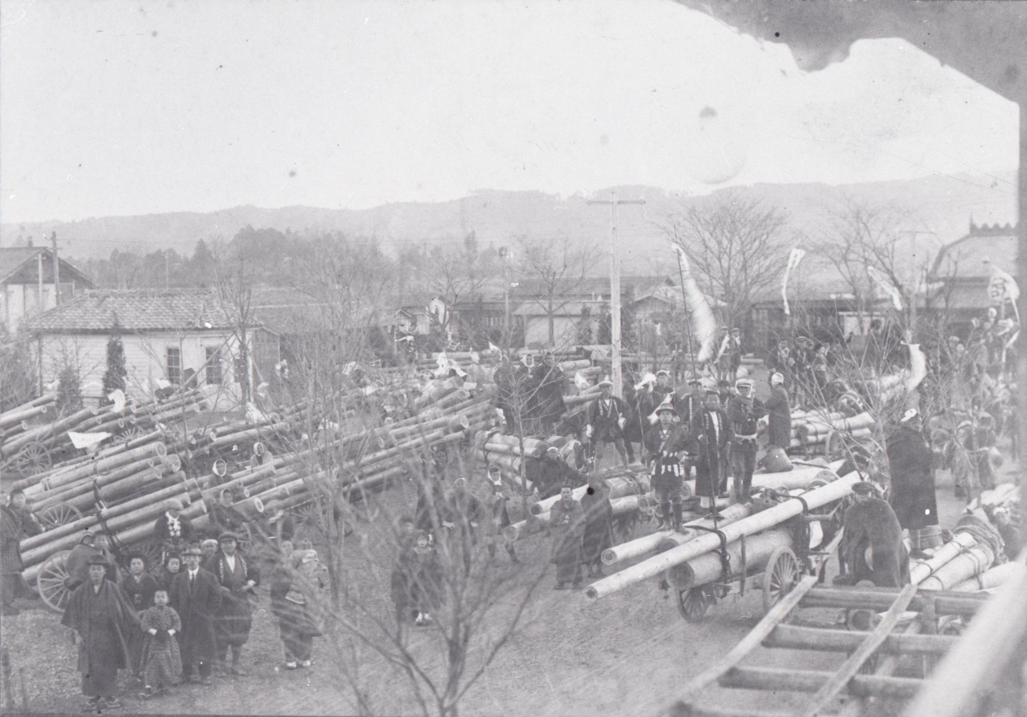 飯能駅前に集まる材木と当時の市民らの様子の写真