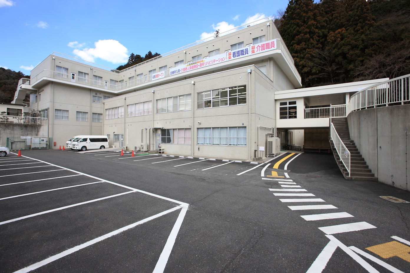 自然豊かな中に建つ広い駐車場が完備された東吾野医療介護センター診療所の外観の写真