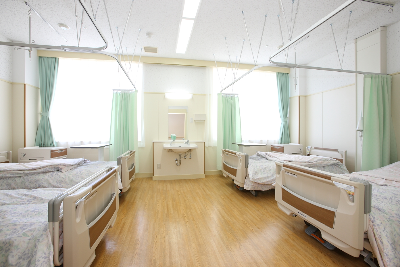 大きな窓からたくさんの光が入る4台のベッドが並んだきれいな病室の写真