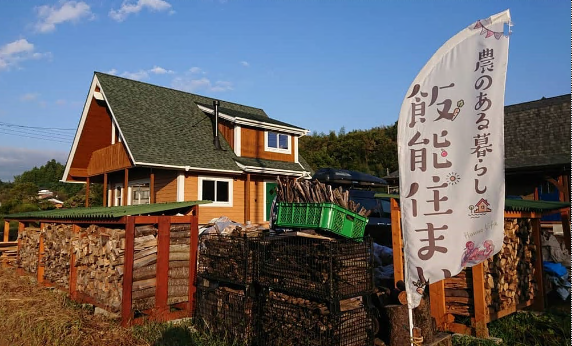 ログハウス風の家屋の前に「飯能住まい」ののぼりが立っている写真